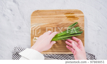 Flat lay. Step by step. Chopping organic green onions on a wood cutting board. Flat lay. Step by step. Chopping organic green onions on a wood cutting board. 97869851