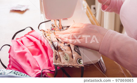 Sewing cotton face mask with a sewing machine for coronavirus outbreak. Sewing cotton face mask with a sewing machine for coronavirus outbreak. 97869865