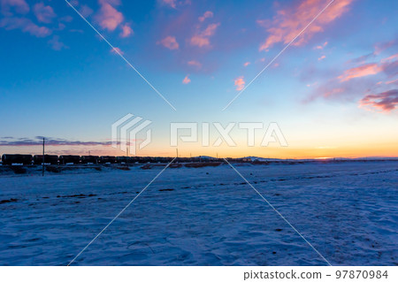 A train running through a snowy field and the sky approaching dawn in Mongolia in the middle of winter 97870984