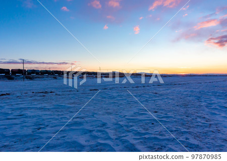 A train running through a snowy field and the sky approaching dawn in Mongolia in the middle of winter 97870985