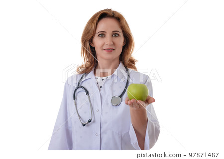 Attractive female doctor with a white coat smiling and holding an apple. Cheerful medical nutritionist recommending a healthy diet to a patient Attractive female doctor with a white coat smiling and holding an apple. Cheerful medical nutritionist recommending a healthy diet to a patient 97871487