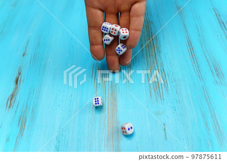 Hand throws dice on the blue wooden playing field. Luck and excitement. Concept Board games strategy 97875611