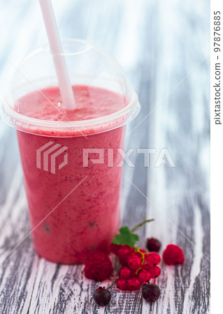 Closeup shot berries milkshake in plastic cup with ingredients on wooden background. Selective focus Closeup shot berries milkshake in plastic cup with ingredients on wooden background. Selective focus 97876885