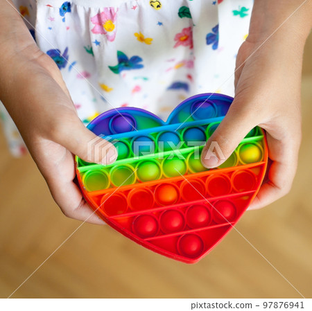 Girl holding heart shaped pop it toy Girl holding heart shaped pop it toy 97876941