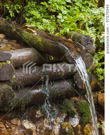 Mountain brook. Wooden log well. Mountain brook. Wooden log well. 97876944