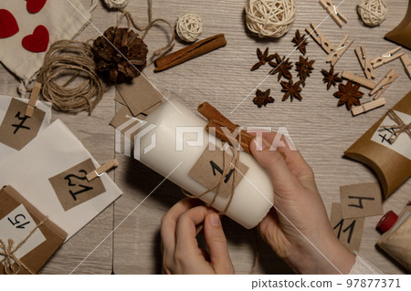 Unrecognizable young woman paint numbers on candles. Female making homemade advent calendar Made with your own hands step by step DIY crafts do it yourself. Preparation to christmas concept. Seasonal 97877371