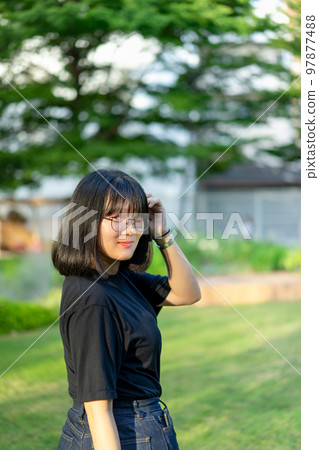 A Portrait of the Asian glassese Thai woman is standing in the garden in the morning. A Portrait of the Asian glassese Thai woman is standing in the garden in the morning. 97877488