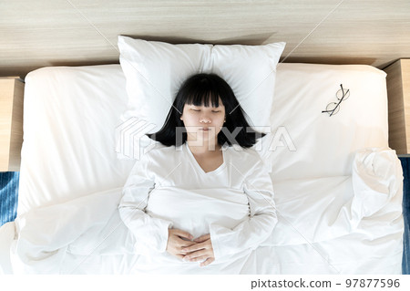 Asian woman sleeps on white bed after exhausted and tried all day. Asian woman sleeps on white bed after exhausted and tried all day. 97877596