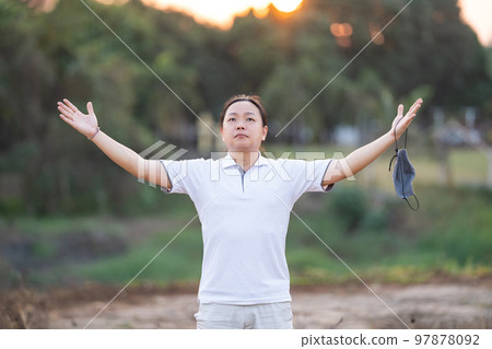 Asian Man take off mask and rise his hand up in golden twilight time. Asian Man take off mask and rise his hand up in golden twilight time. 97878092