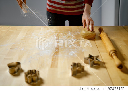 Woman sprinkles flour on table to roll out dough Woman sprinkles flour on table to roll out dough 97878151