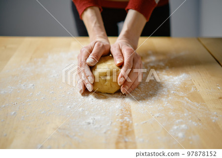 Woman kneads dough with her hands Woman kneads dough with her hands 97878152