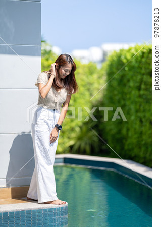 Asian woman is looking into under the pool beside the building with the tree background environment. Asian woman is looking into under the pool beside the building with the tree background environment. 97878213