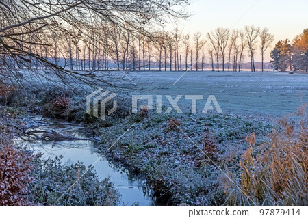 Image of a stream flowing through a winter forest 97879414