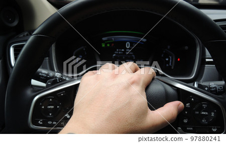 Fingers of human hand on a steering wheel center cap in car with illuminated dashboard stock photo Fingers of human hand on a steering wheel center cap in car with illuminated dashboard stock photo 97880241