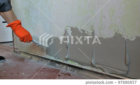 plastic mortar applied on a room wall in thick layers to level the surface, the plasterer applies the mortar on the wall texture with a spatula angle view copy space plastic mortar applied on a room wall in thick layers to level the surface, the plasterer applies the mortar on the wall texture with a spatula angle view copy space 97880857