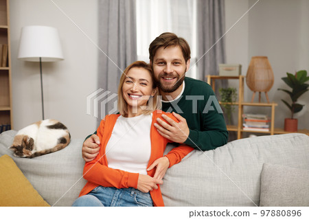 Romantic Couple Embracing Sofa. Happy Couple Relaxing On Couch At Home 97880896