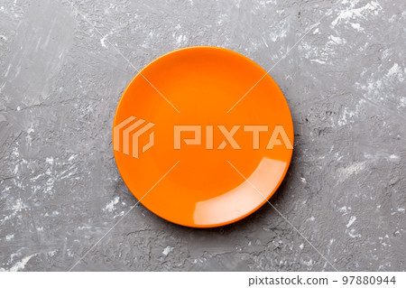 Top view of empty orange plate on cement background. Empty space for your design Top view of empty orange plate on cement background. Empty space for your design 97880944
