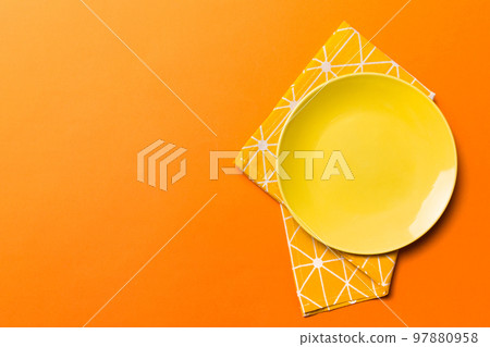 Top view on colored background empty round yellow plate on tablecloth for food. Empty dish on napkin with space for your design Top view on colored background empty round yellow plate on tablecloth for food. Empty dish on napkin with space for your design 97880958