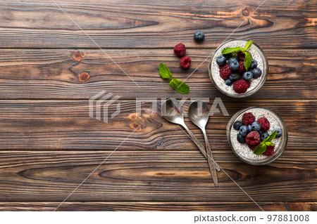 Healthy breakfast or morning with chia seeds vanilla pudding raspberry and blueberry berries on table background, vegetarian food, diet and health concept. Chia pudding with raspberry and blueberry 97881008