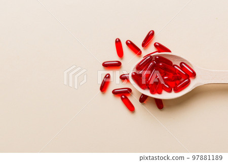 Vitamin capsules in a spoon on a colored background. Pills served as a healthy meal. Red soft gel vitamin supplement capsules on spoon Vitamin capsules in a spoon on a colored background. Pills served as a healthy meal. Red soft gel vitamin supplement capsules on spoon 97881189