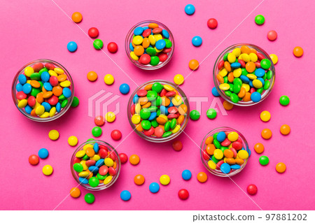different colored round candy in bowl and jars. Top view of large variety sweets and candies with copy space different colored round candy in bowl and jars. Top view of large variety sweets and candies with copy space 97881202