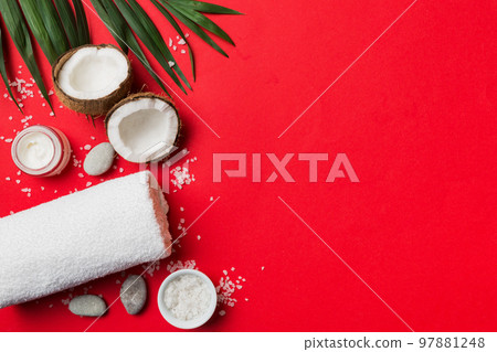 Coconut with jars of coconut oil and cosmetic cream on colored background. Top view. Free space for your text. Natural spa coconut cosmetics and organic treatment concept Coconut Spa composition 97881248