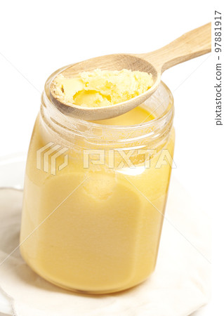 Ghee in jar and wooden spoon isolated on white background. Ghee in jar and wooden spoon isolated on white background. 97881917