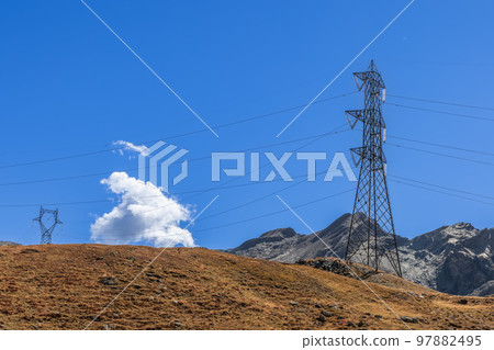 Wires of high-voltage power line laid along granite slopes overgrown with withered autumn grass 97882495