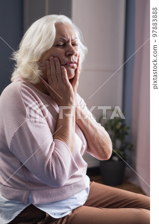 Woman touching mouth with hand with painful expression because of toothache  97883888