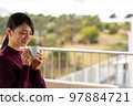 A woman relaxing on the terrace with a cup of coffee 97884721