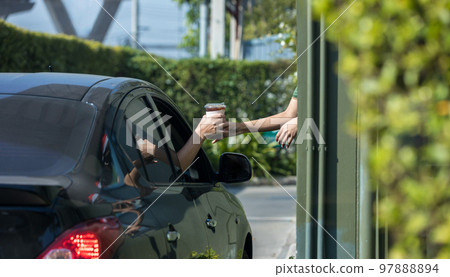 Hand Man in car receiving coffee in drive thru fast food restaurant. 97888894