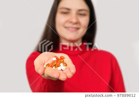A woman smiling stretches out her hand with a handful of colorful pills and capsules A woman smiling stretches out her hand with a handful of colorful pills and capsules 97889012