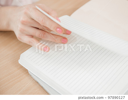 Close up of woman's hands at work, she write the plan of the day in a notebook at her workplace. Work, learning, student and home office concept Close up of woman's hands at work, she write the plan of the day in a notebook at her workplace. Work, learning, student and home office concept 97890127