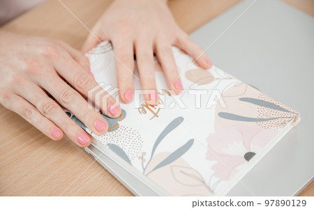 Close up of a woman's hands writing in a notepad placed on a wooden table, home office and work concept, plans and business meeting Close up of a woman's hands writing in a notepad placed on a wooden table, home office and work concept, plans and business meeting 97890129