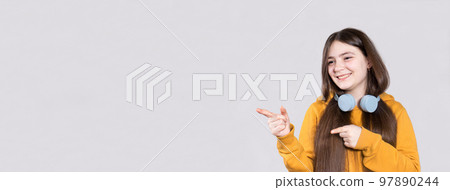 A cheerful teenage girl with long hair shows her fingers to the side in place for the text. Long horizontal banner for advertising, offer for children's clothing store or training for children A cheerful teenage girl with long hair shows her fingers to the side in place for the text. Long horizontal banner for advertising, offer for children's clothing store or training for children 97890244