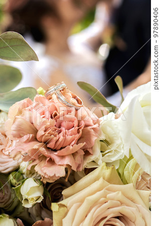 Gold wedding rings on a bride's bouquet of pink, yellow and white delicate roses. Gold wedding rings on a bride's bouquet of pink, yellow and white delicate roses. 97890406