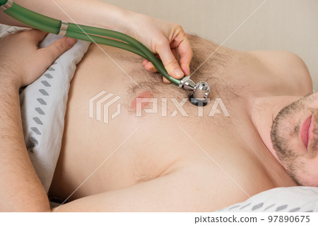 The doctor auscultizes the heart of a 30-year-old male patient with a phonendoscope, diagnosing heart disease in humans 97890675