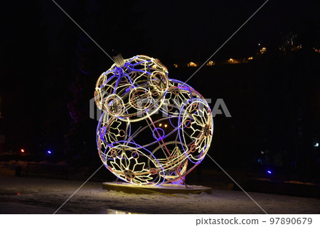 Sculptures with lighting in the form of Christmas tree toys in the park at night. Beautiful giant Christmas tree toys with lights in the city. Sculptures with illumination. 97890679