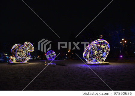 Sculptures with lighting in the form of Christmas tree toys in the park at night. Beautiful giant Christmas tree toys with lights in the city. Sculptures with illumination. 97890686