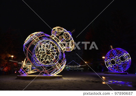 Sculptures with lighting in the form of Christmas tree toys in the park at night. Beautiful giant Christmas tree toys with lights in the city. Sculptures with illumination. 97890687
