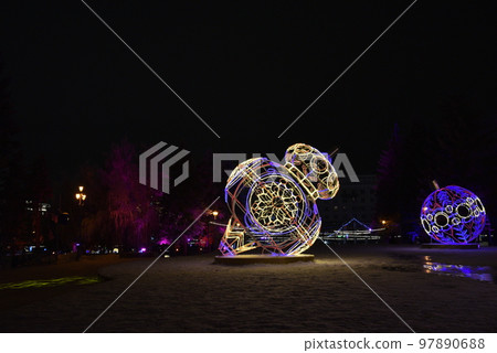 Sculptures with lighting in the form of Christmas tree toys in the park at night. Beautiful giant Christmas tree toys with lights in the city. Sculptures with illumination. 97890688