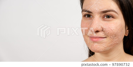 A young brunette woman makes cleansing facial treatments - a mask or scrub to cleanse and nourish the skin, banner with place for text. 97890732