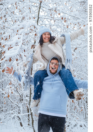 It is a snowy forest with a woman piggybacking on a man It is a snowy forest with a woman piggybacking on a man 97890882
