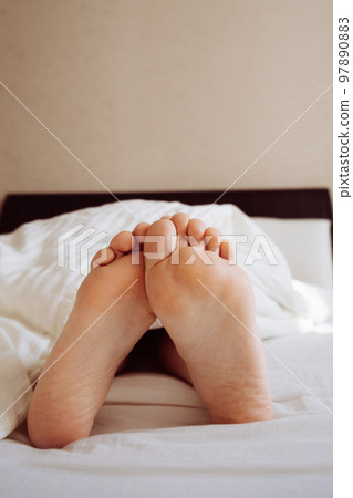 Under the blankets, the woman's legs stick out 97890883