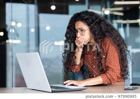 Businesswoman has severe nausea, latin american woman at work sick, working sitting at table with laptop inside office. Businesswoman has severe nausea, latin american woman at work sick, working sitting at table with laptop inside office. 97890985
