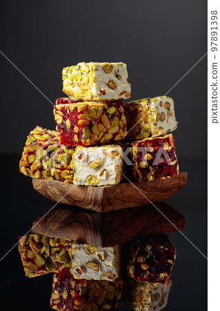 Turkish delight in a wooden dish on a black reflective background. 97891398