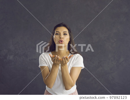Beautiful friendly woman sends an air kiss to the camera showing her good feelings. Beautiful friendly woman sends an air kiss to the camera showing her good feelings. 97892123