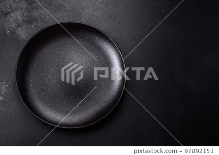 Empty beautiful black ceramic plate on a dark concrete background 97892151