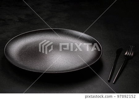 Empty beautiful black ceramic plate on a dark concrete background 97892152