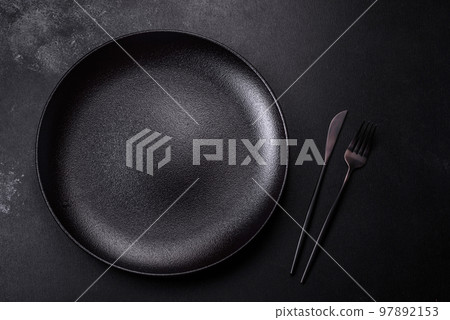 Empty beautiful black ceramic plate on a dark concrete background Empty beautiful black ceramic plate on a dark concrete background 97892153